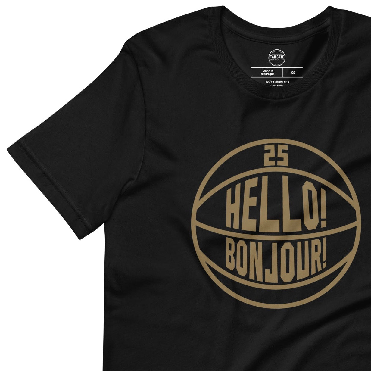 This image details the graphic design "Hello! Bonjour!". In the image, the words are built into a basketball and feature Chris Boucher's number 25. The Toronto Raptors' announcer, Jack Armstrong, loves to shout out Hello! Bonjour! when Chris Boucher does something exciting on the court. The tee is black and the design is in a gold similar to the Toronto Raptors City Edition colours. This item is exclusive to tailgate mercantile and is available only online.