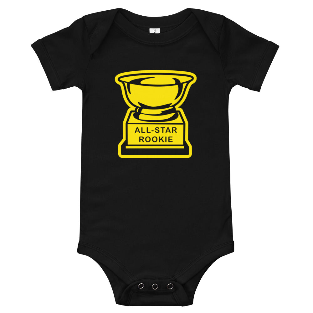 Image of a baby onesie that features a graphic design that looks like a trophy with the words "all star rookie". The trophy in the image is similar to one used on retro baseball cards and major league baseball. This item is exclusive to Tailgate Mercantile and available online only. 
