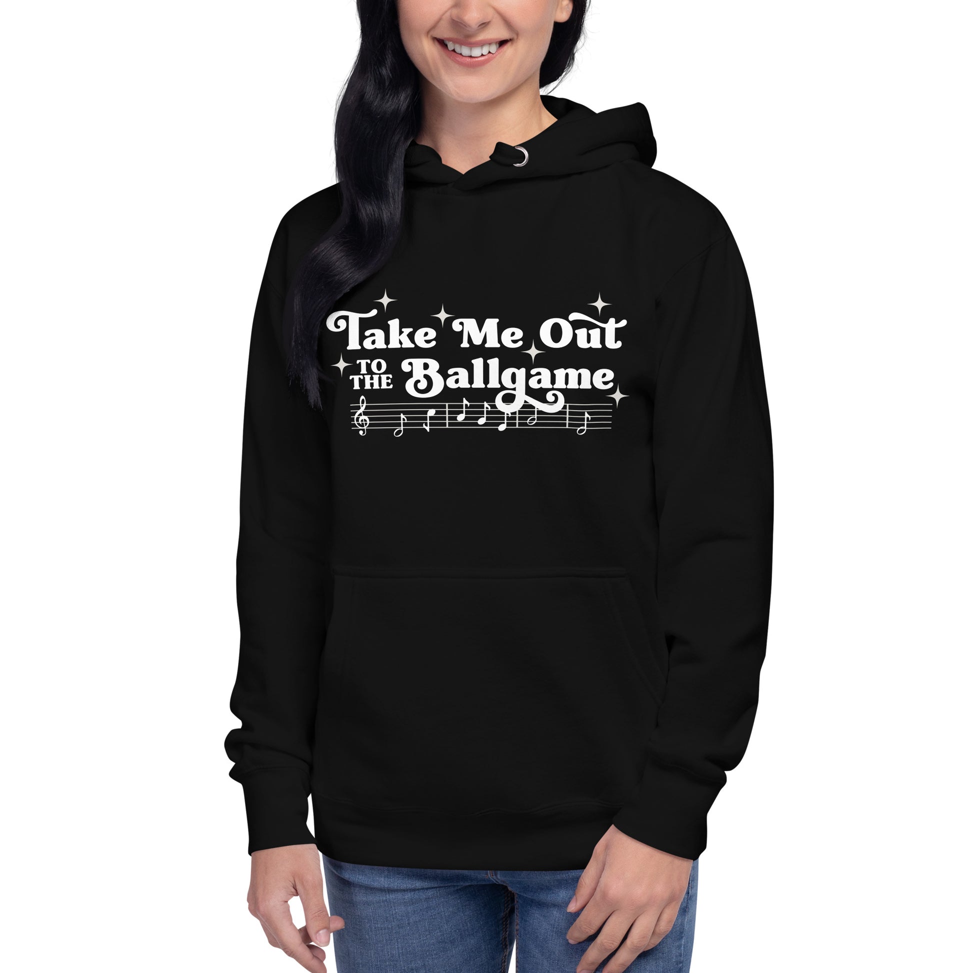 Image of woman wearing black hoodie with design of "Take Me Out to the Ballgame" with coordinating musical notes in white located on centre chest. This design is exclusive to Tailgate Mercantile and available only online.