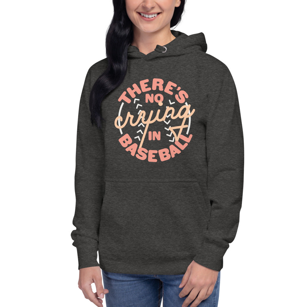 Image of woman wearing heather dark grey hoodie with design of "There's No Crying in Baseball" in peach located on centre chest. There's No Crying in Baseball is an homage to the great AAGPBL women's baseball movie "A League of Their Own". This design is exclusive to Tailgate Mercantile and available only online.