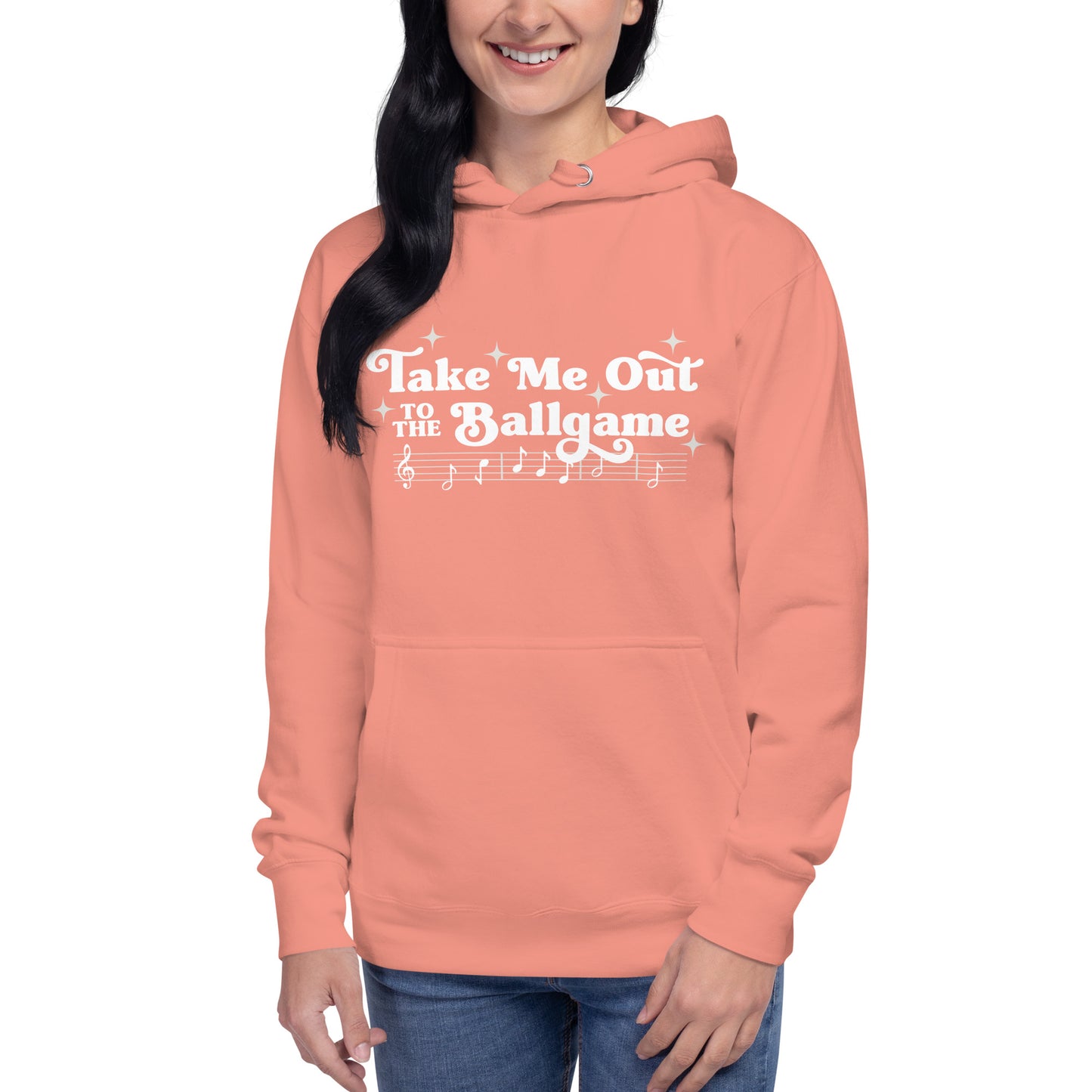 Image of woman wearing peach hoodie with design of "Take Me Out to the Ballgame" with coordinating musical notes in white located on centre chest. This design is exclusive to Tailgate Mercantile and available only online.