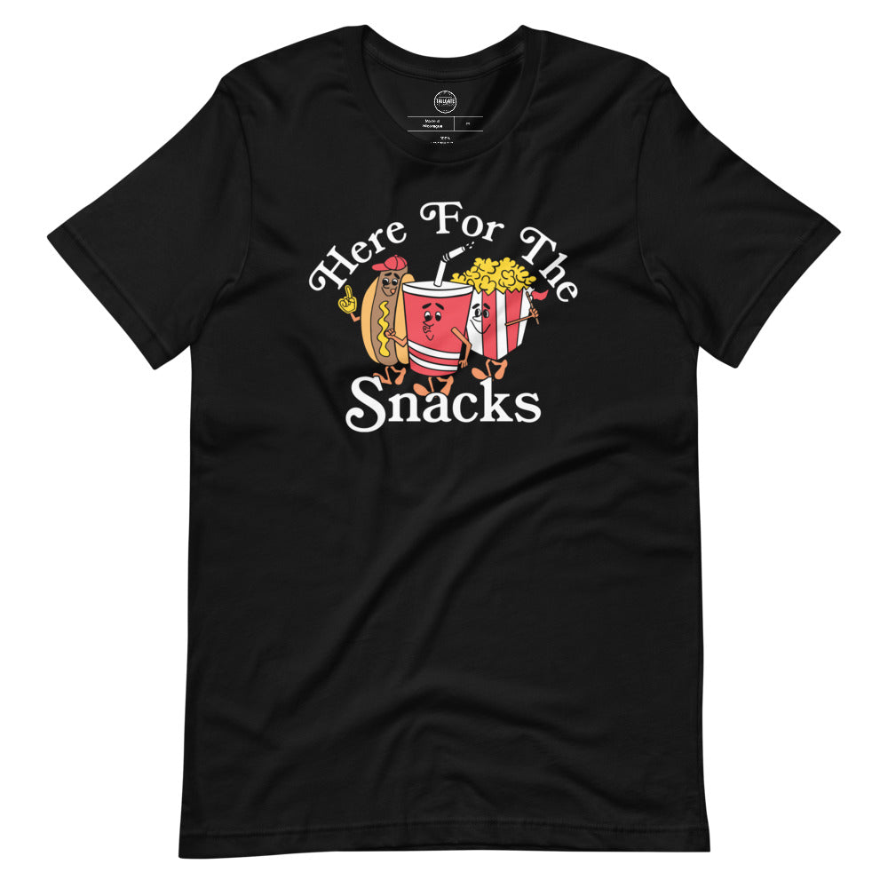 Image of black tee with design of "Here For The Snacks" with cartoon hot dog, soda pop and popcorn located on centre chest. This design is exclusive to Tailgate Mercantile and available only online.