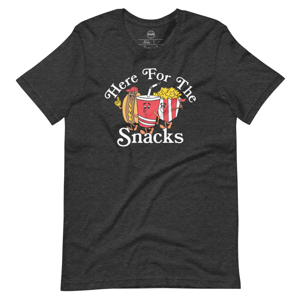 Image of heather dark grey tee with design of "Here For The Snacks" with cartoon hot dog, soda pop and popcorn located on centre chest. This design is exclusive to Tailgate Mercantile and available only online.