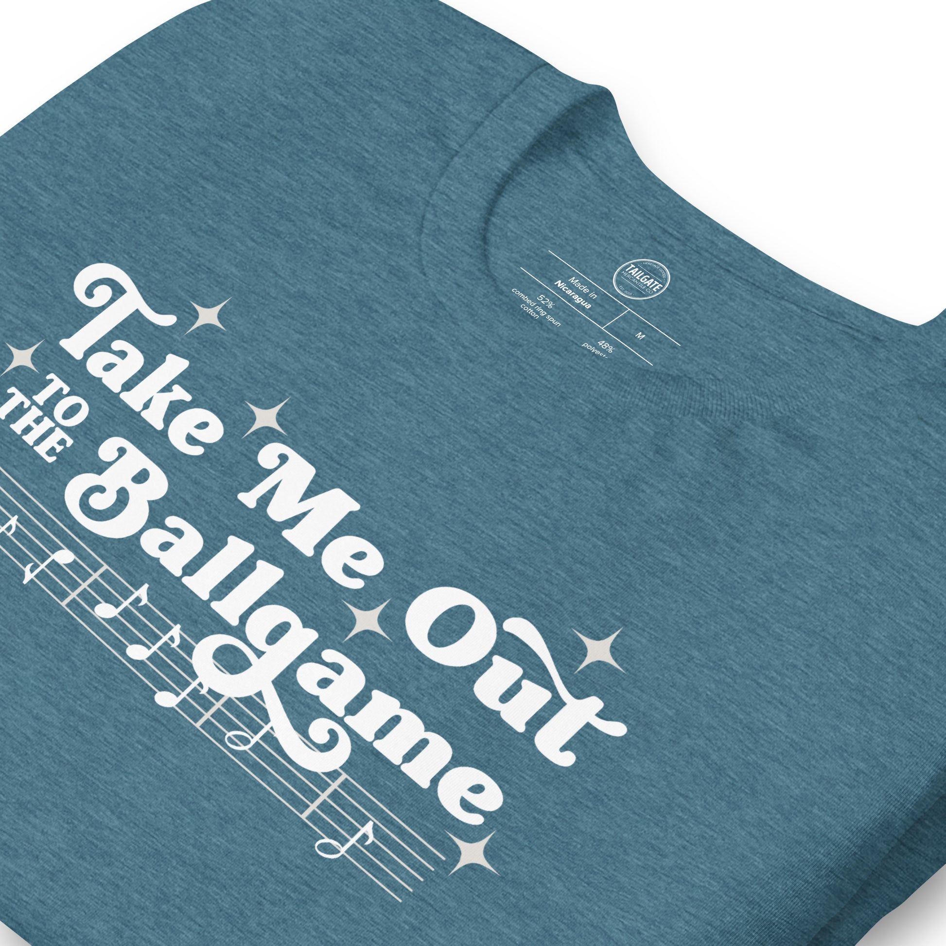 Close up image of heather teal t-shirt with design of "Take Me Out to the Ballgame" with coordinating musical notes in white located on centre chest. This design is exclusive to Tailgate Mercantile and available only online.