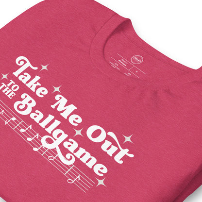 Close up image of heather pink t-shirt with design of "Take Me Out to the Ballgame" with coordinating musical notes in white located on centre chest. This design is exclusive to Tailgate Mercantile and available only online.