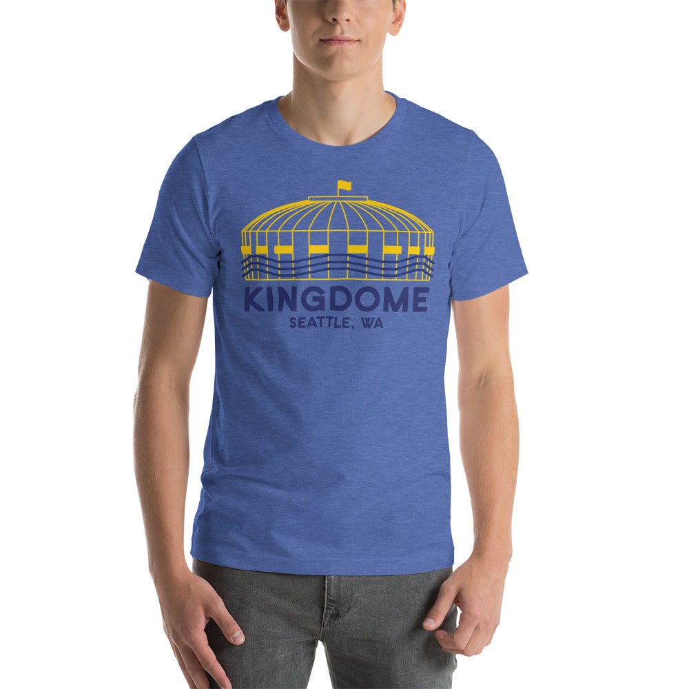 Image of man wearing heather royal blue t-shirt with design of "Kingdome, Seattle, WA" illustrated ballpark completed in retro Seattle Mariners colours located on centre chest. This design is exclusive to Tailgate Mercantile and available only online.